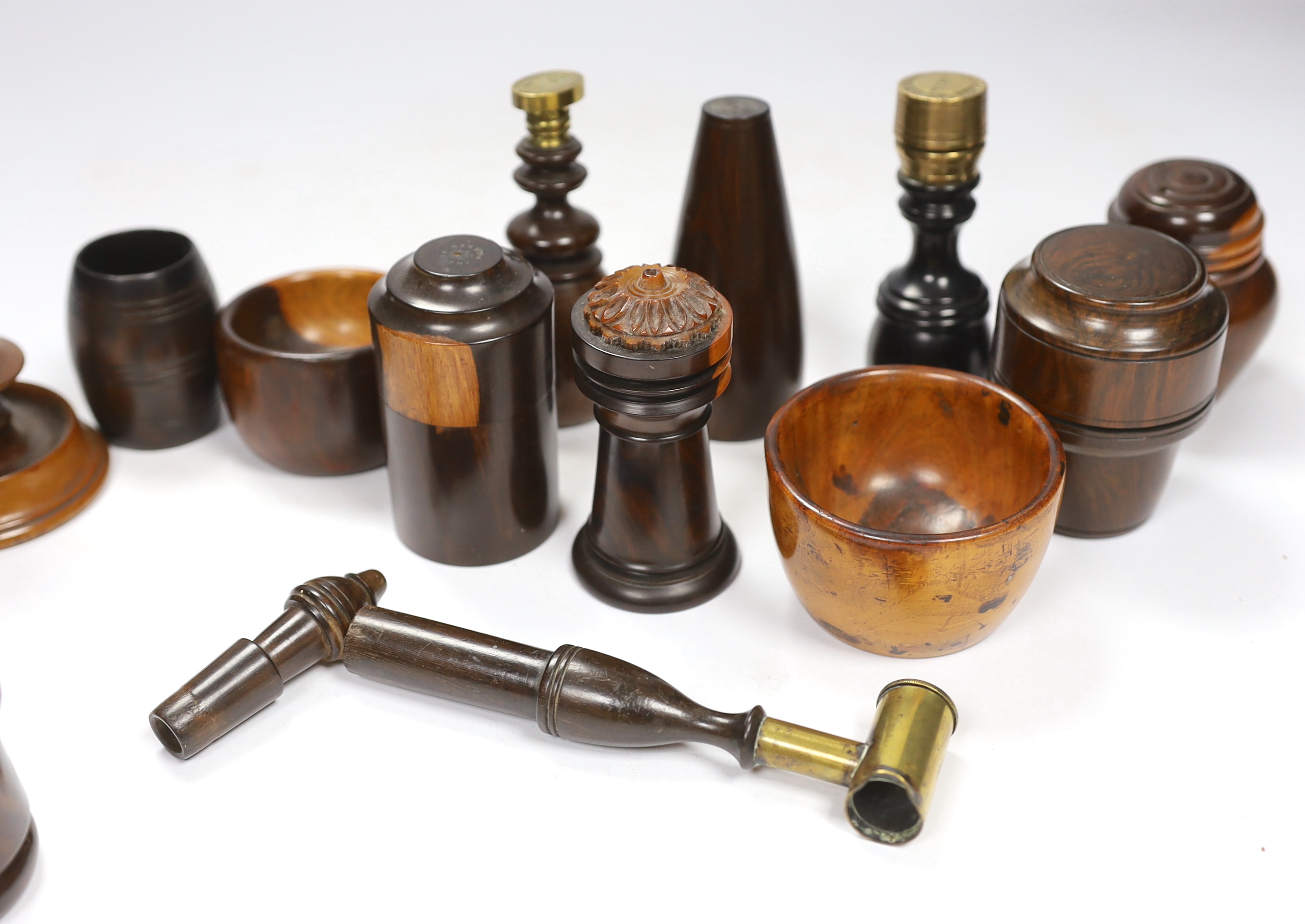 A collection of 19th/20th century lignum vitae vessels and desk items, to include a pepper pot, salt pot, two desk seals, a whistle, a candlestick etc.